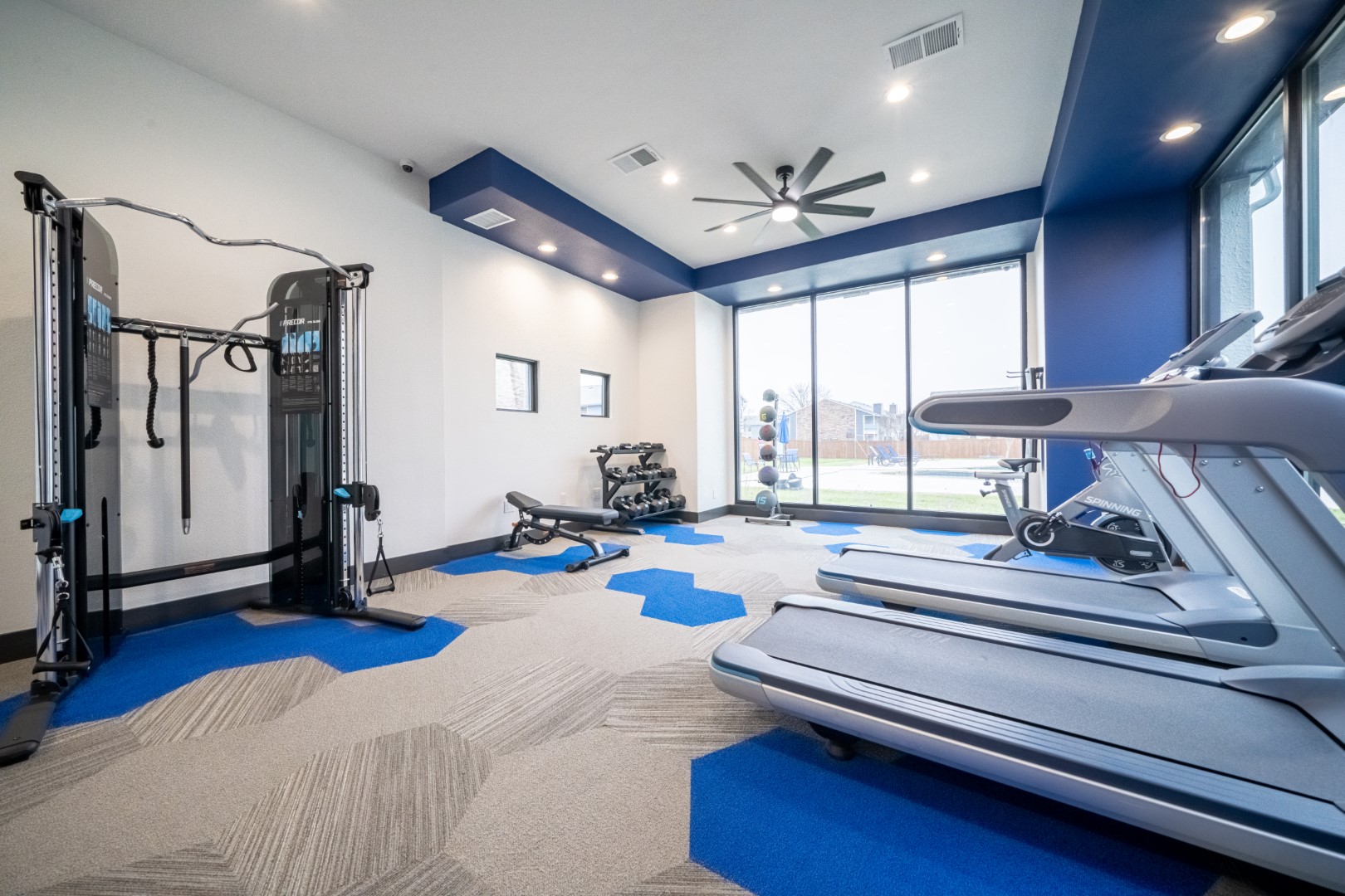 a gym room with blue carpet and tread machines at The Hendrix Apartments