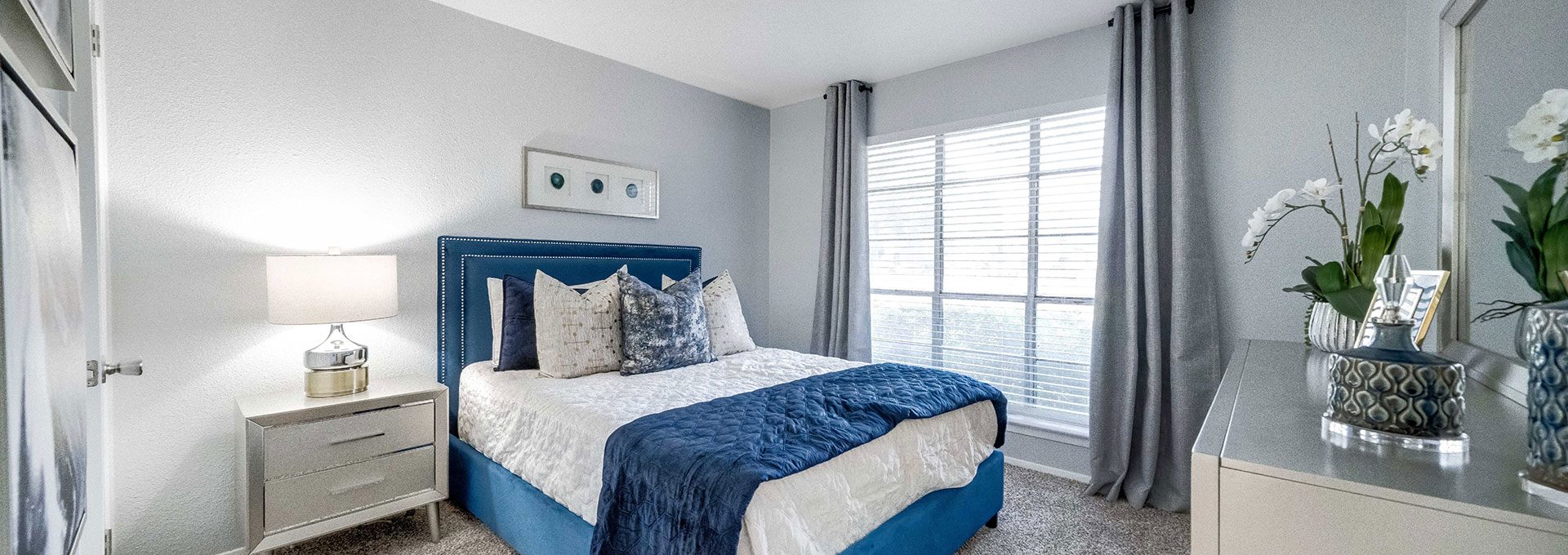 a bedroom with a blue bed and white carpet at The Hendrix Apartments